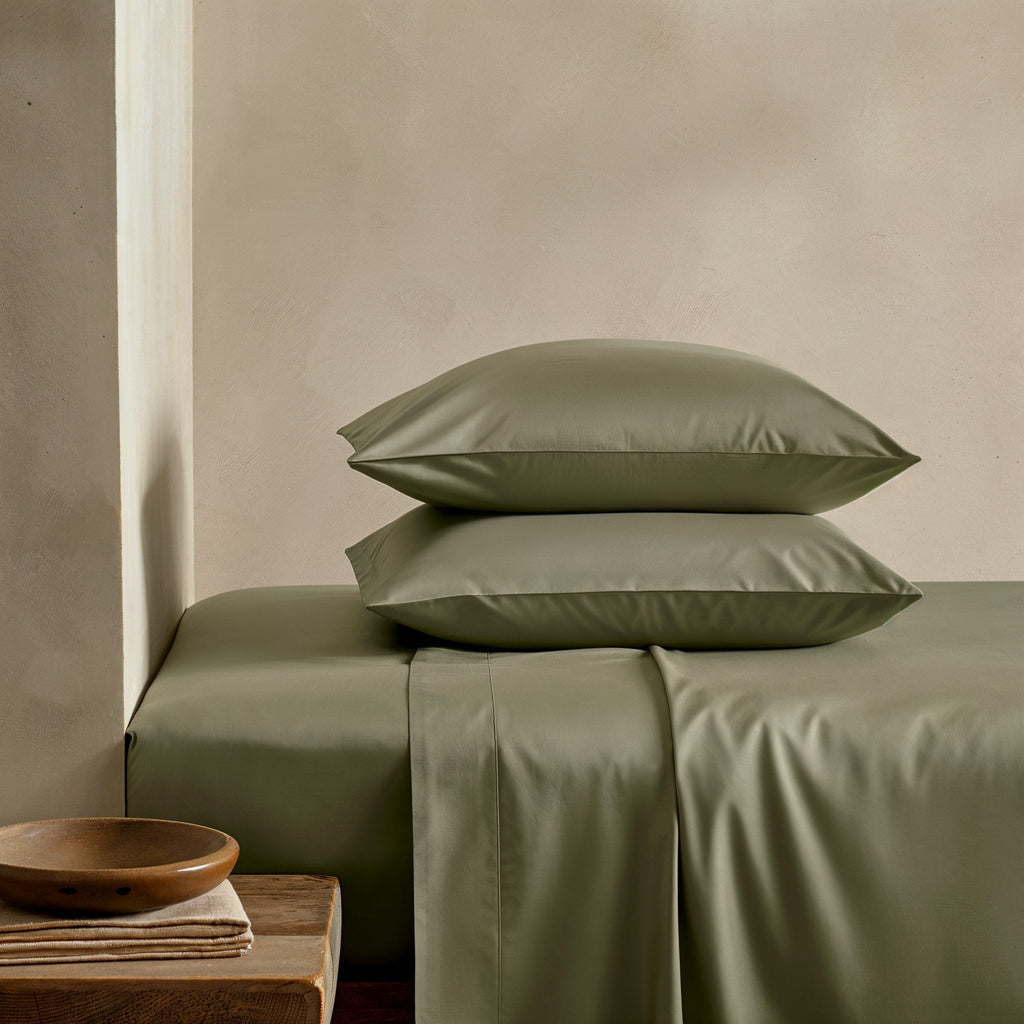 Sateen sheet set in olive green with matching pillowcases, neatly arranged on bed
