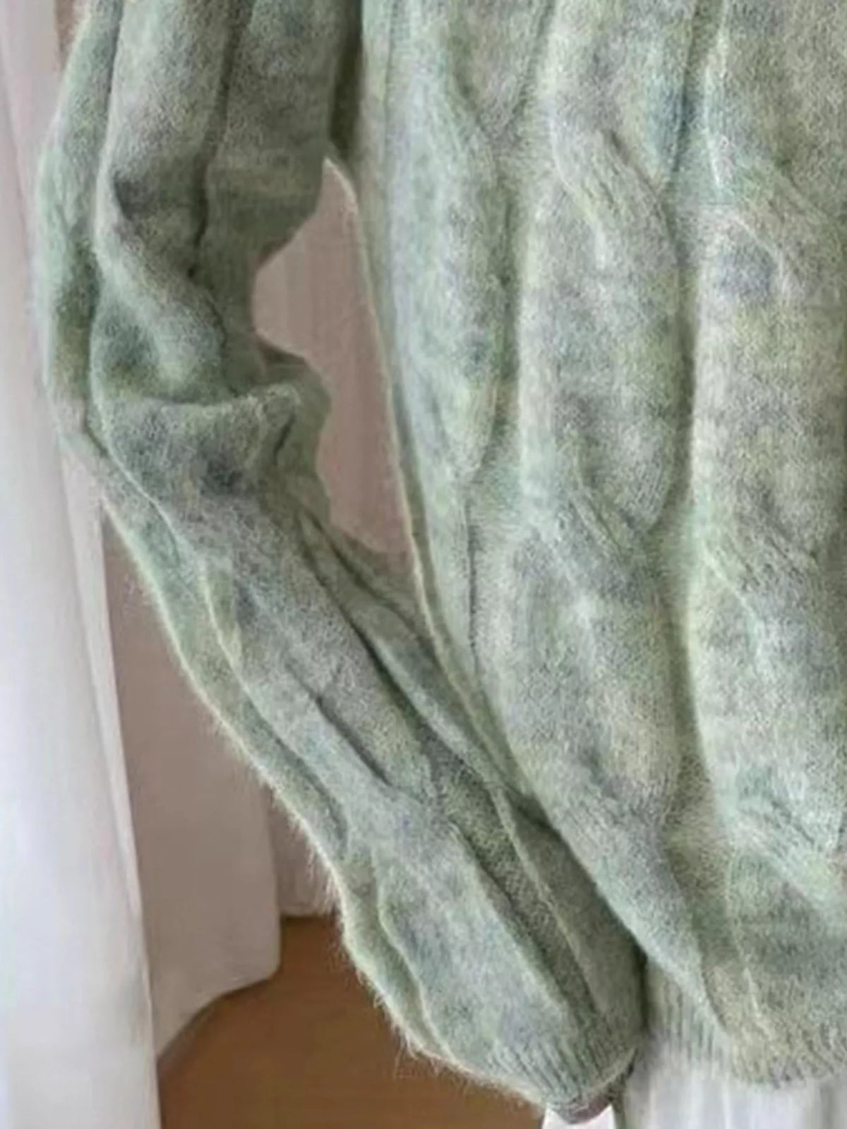 Green cable-knit sweater with long sleeves and ribbed hem detail