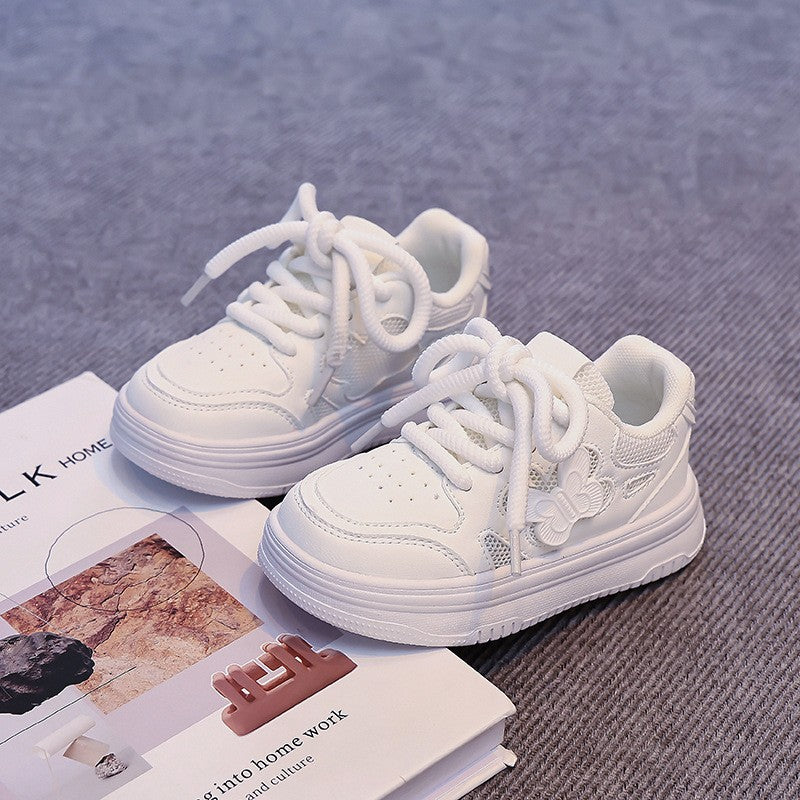 White kids' low-top sneakers with lace-up closure and perforated toe, side view pair.