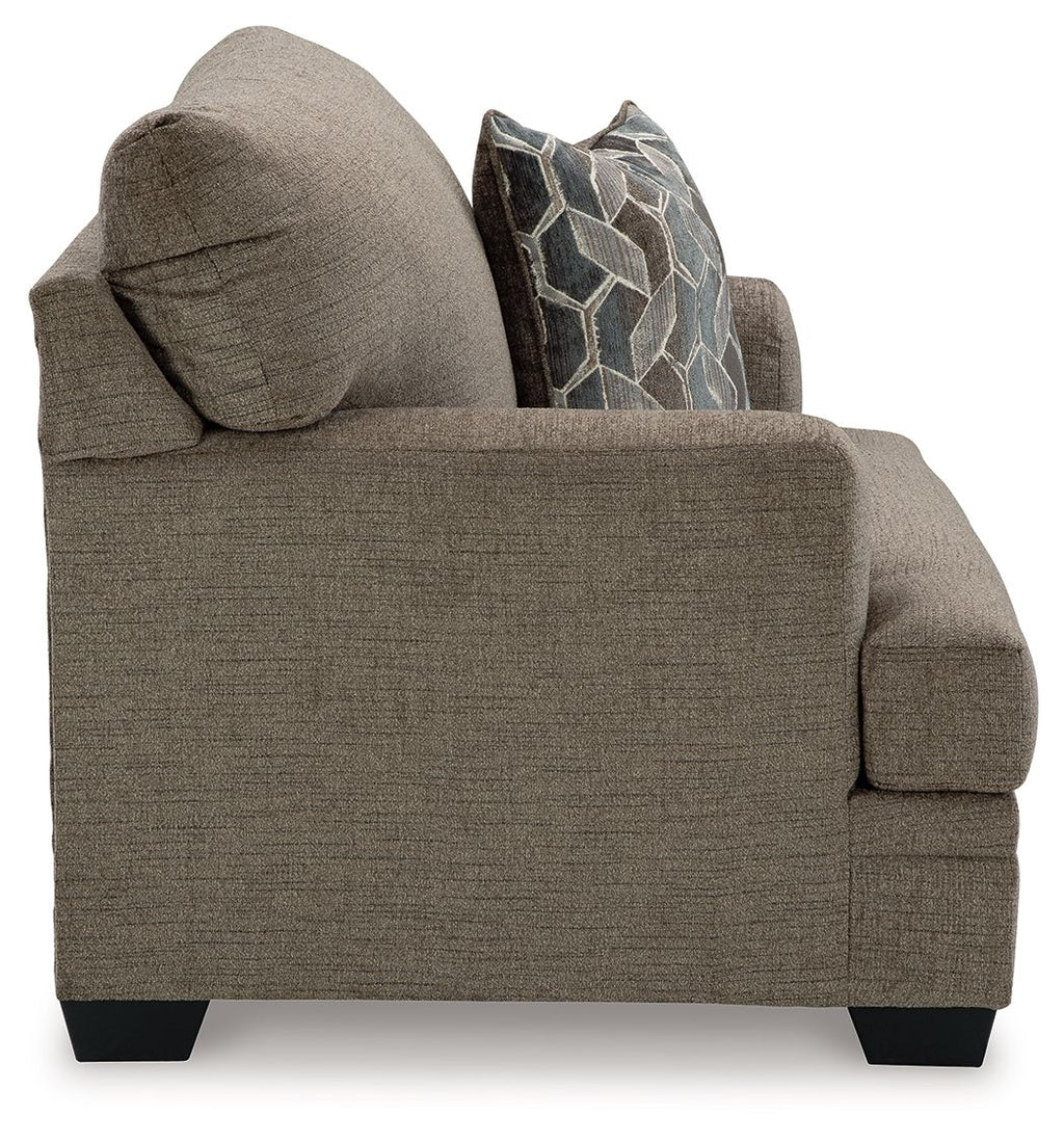 Upholstered chaise loveseat in brown fabric with decorative geometric accent pillows