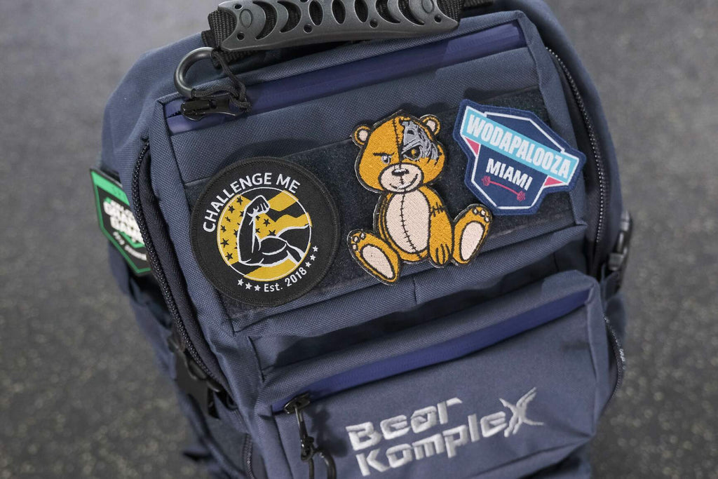 BKX navy blue military backpack close-up with stitched patches and front zip pocket