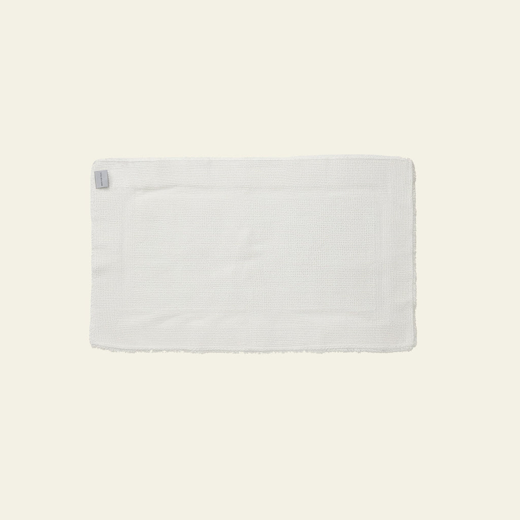 White plush bath mat with small fabric tag and clean edges