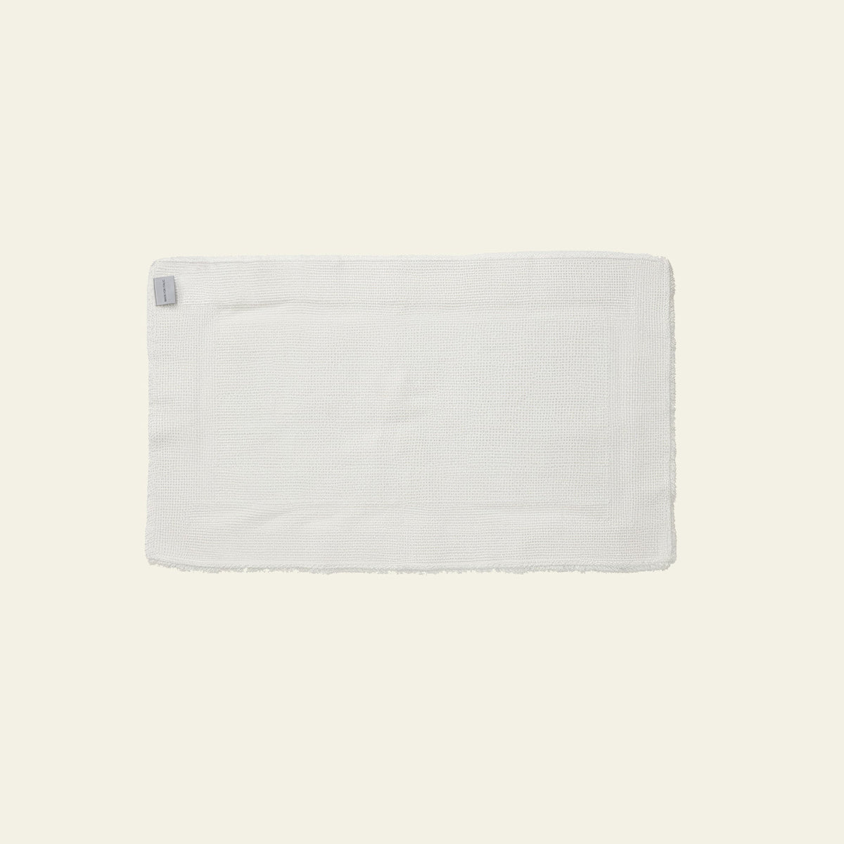 White plush bath mat with small fabric tag and clean edges