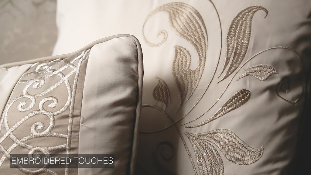 Ivory pillow with gold embroidered scroll motif and bordered edge