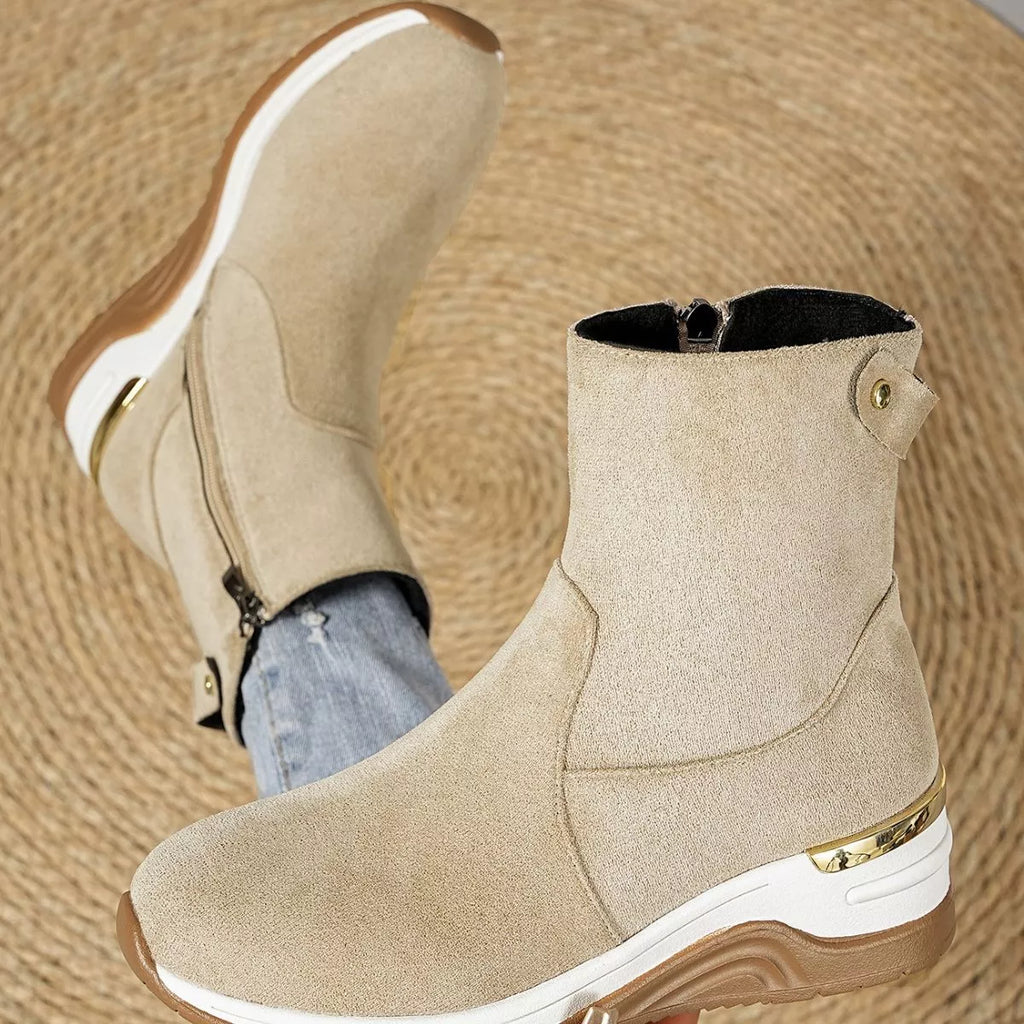 Beige suede ankle boots close-up, wedge sole with gold trim and side zipper