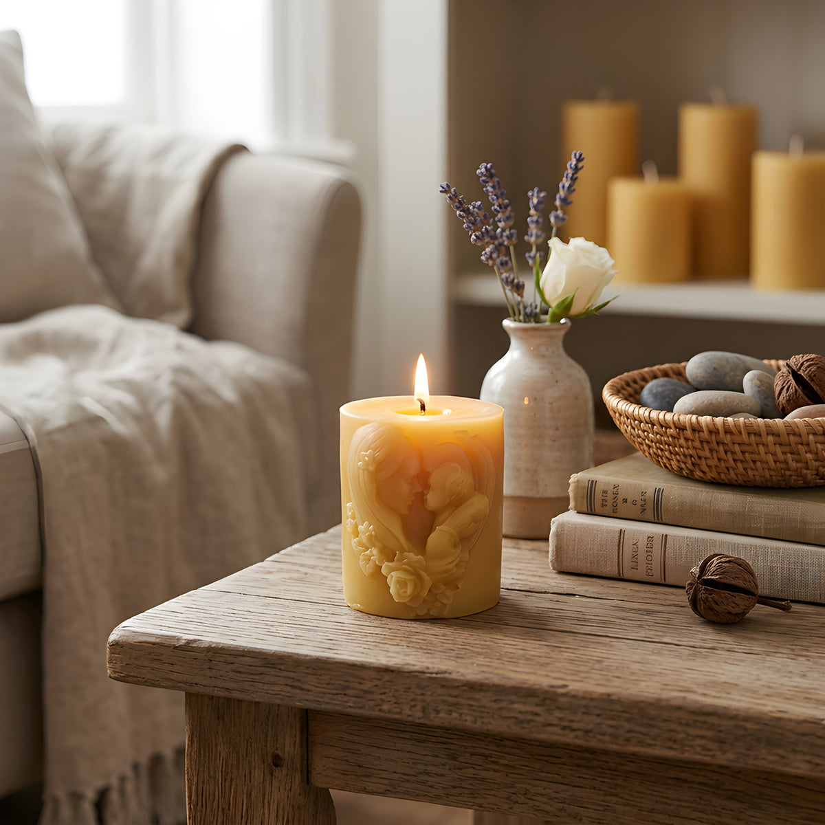 Lit honey beeswax candle with embossed floral mother figure, wick centered on top