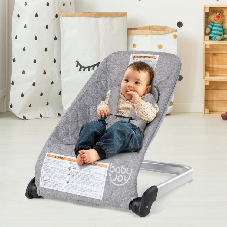 Gray baby bouncer seat with 5-point harness, baby seated on raised base