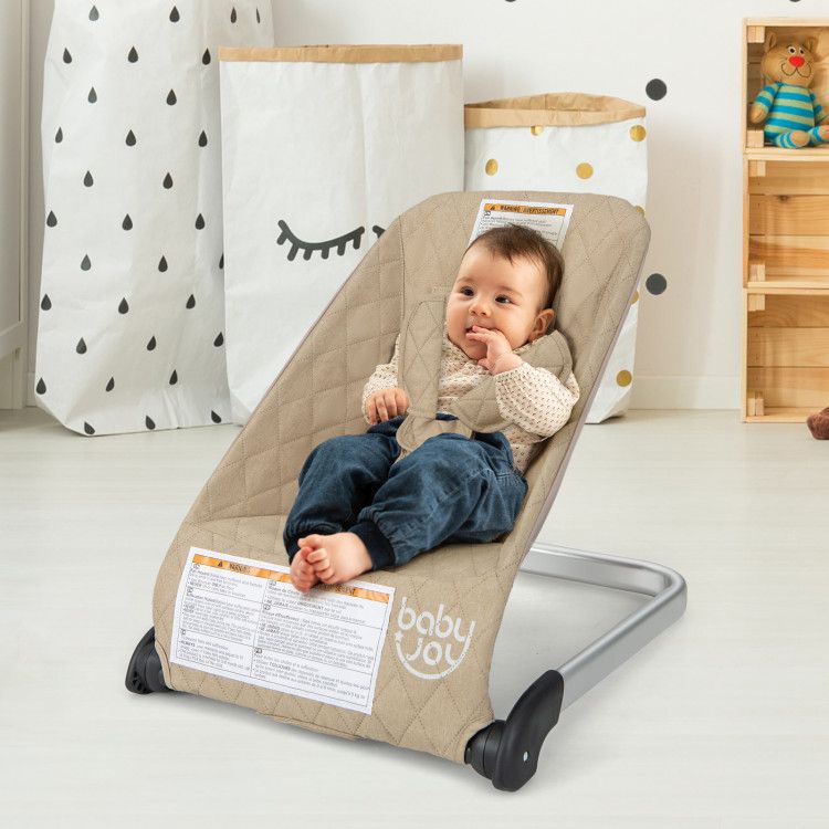 Baby bouncer seat with light beige quilted cover and black rocker base, baby seated