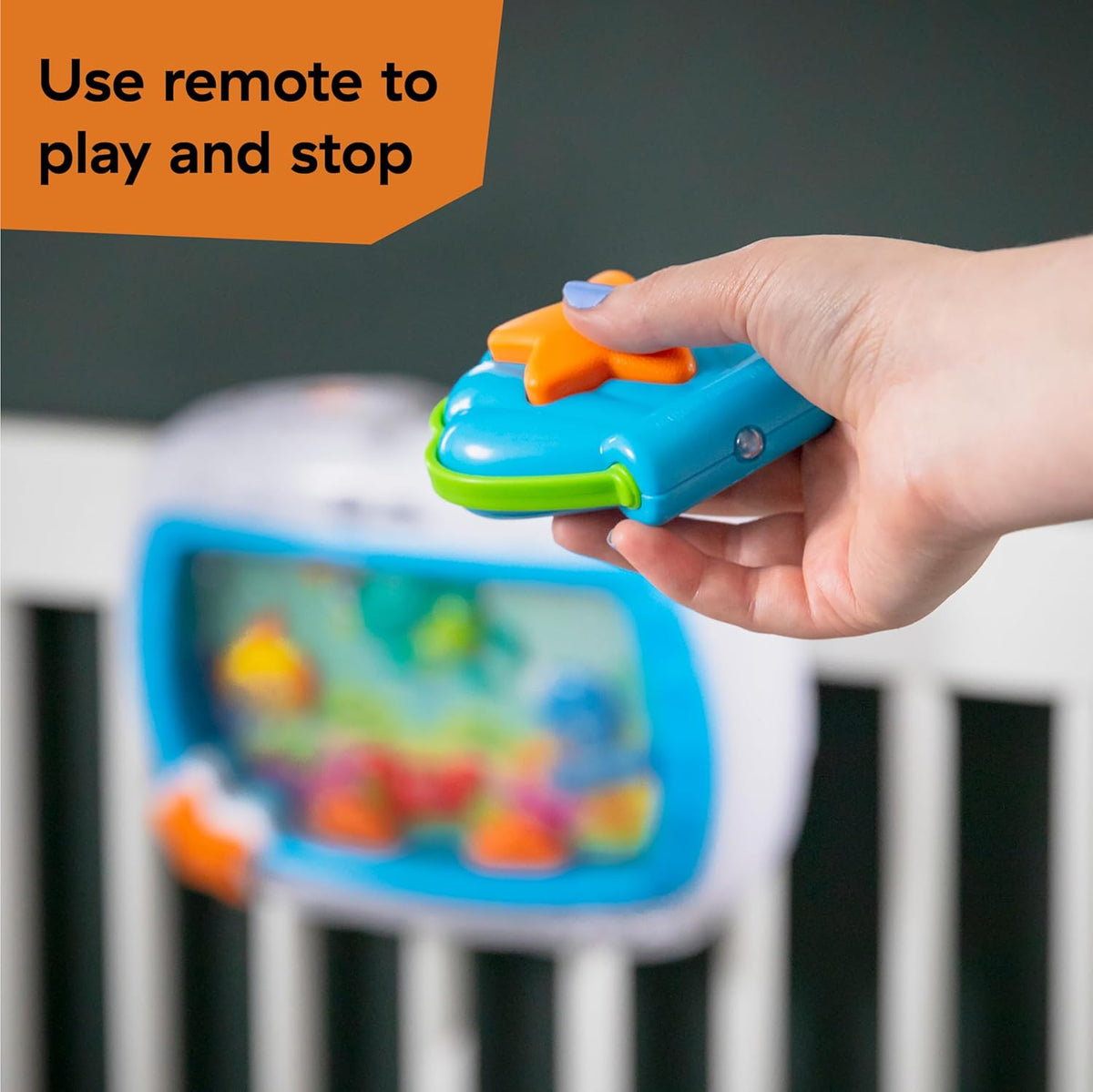 Baby Einstein crib toy remote-style controller held in hand with orange and green buttons