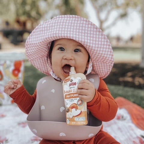 Holle Organic Banana Llama fruit purée pouch held by a baby