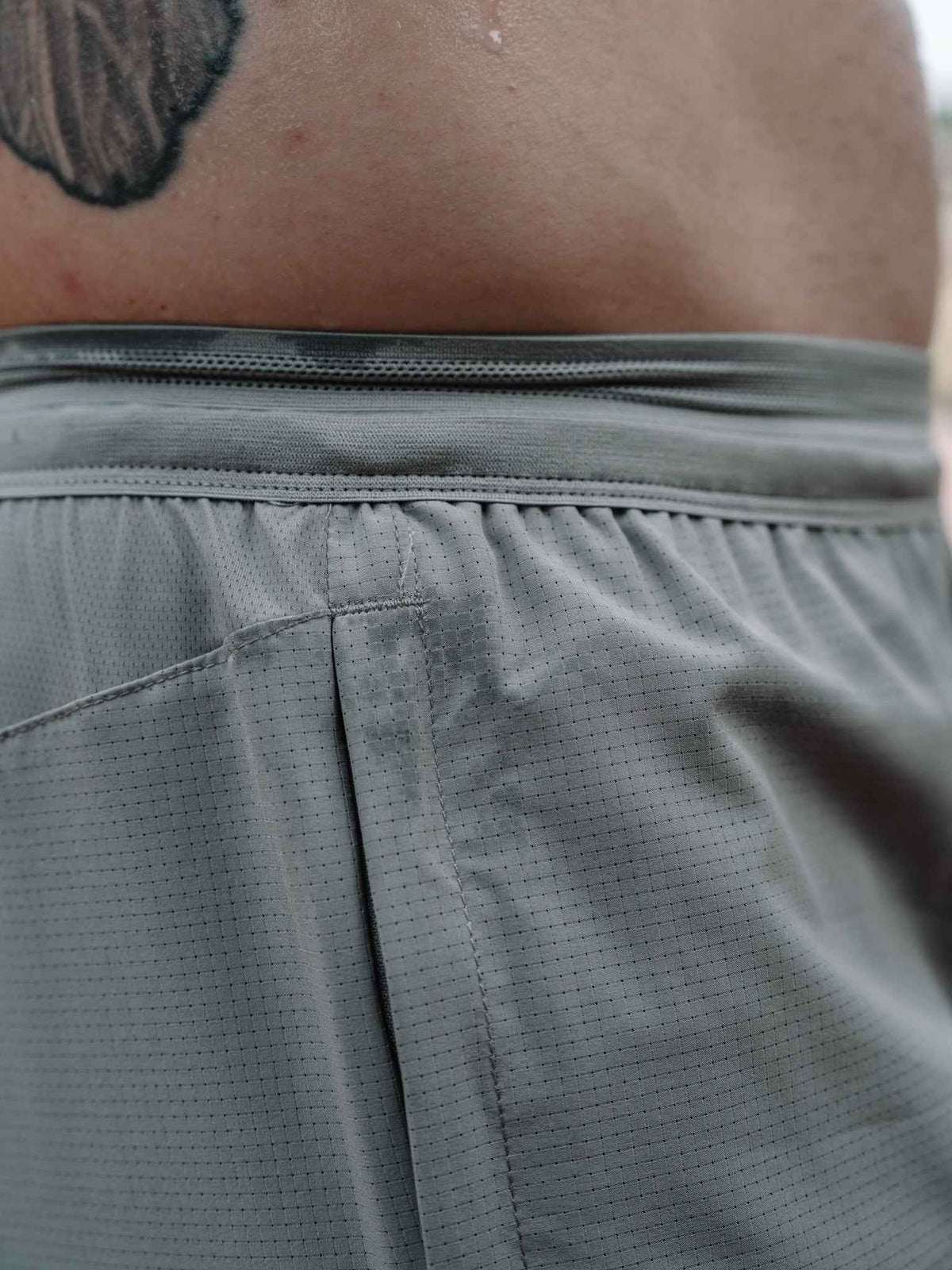 Gray shorts waistband and back panel close-up with stitched pleats and seams.