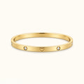 Gold-tone heart bangle bracelet with two round diamond-like stones