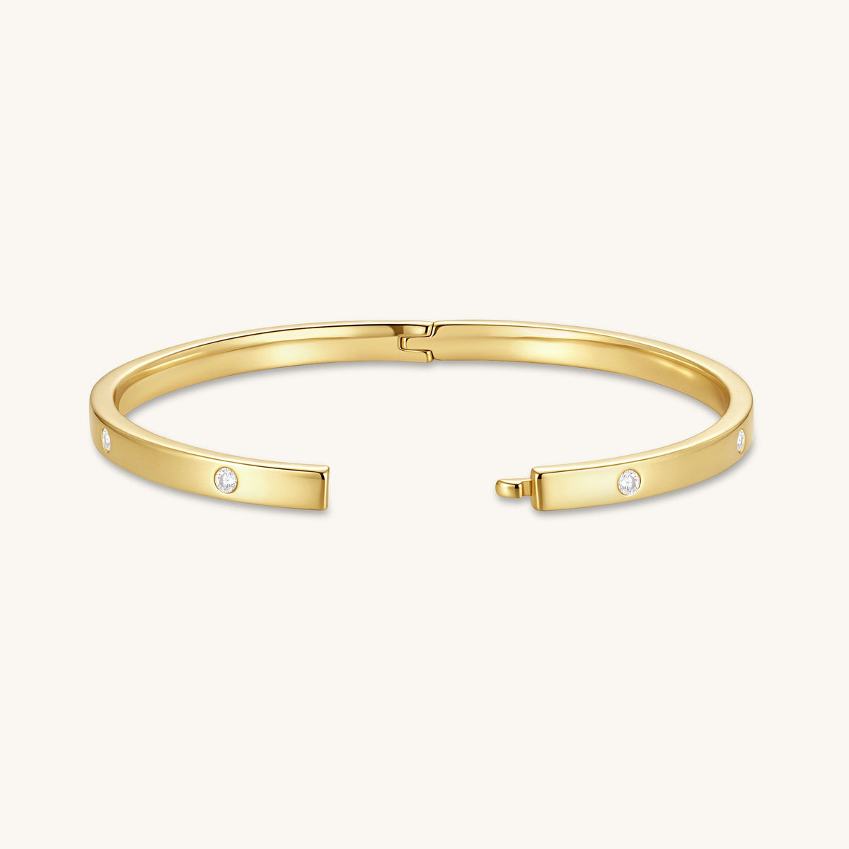 Gold-tone hinged bangle with round diamonds on the ends and center clasp, laid flat