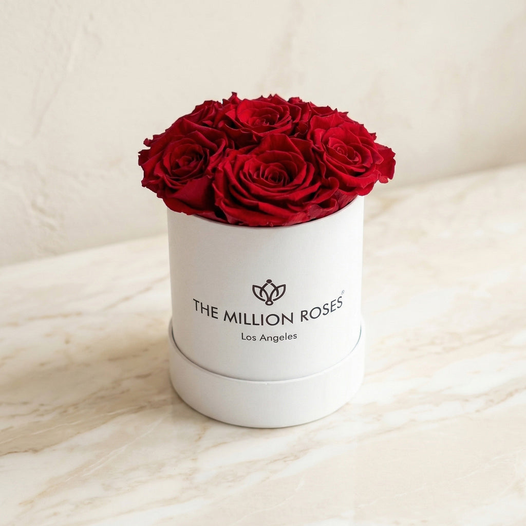 White cylindrical gift box with red roses and front logo label
