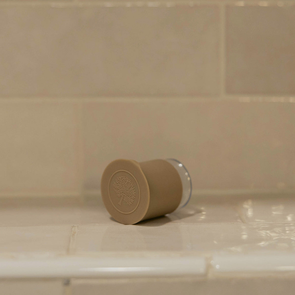 Beige silicone bath hook placed on a bathtub ledge