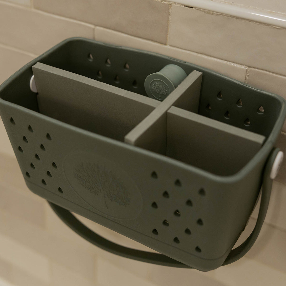 Silicone bath hook attached to a bathroom caddy with perforated compartments