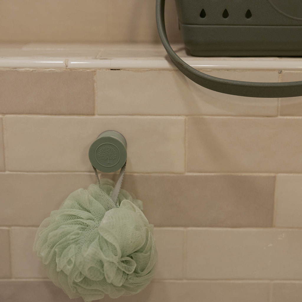 Mint silicone bath hook holding a mesh bath sponge on the shower wall