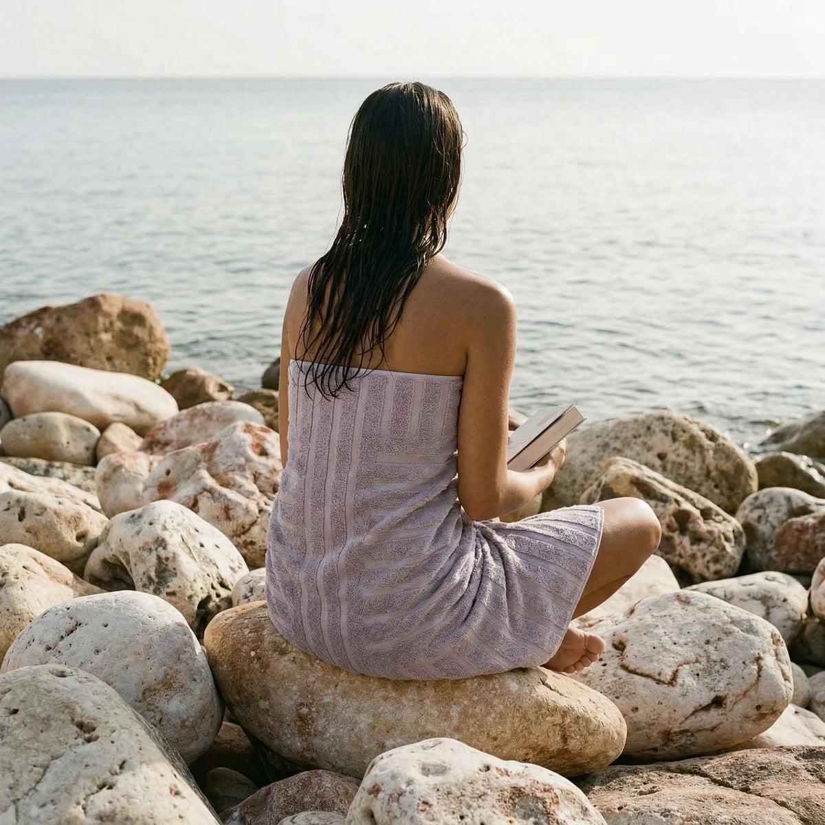 Lilac cotton wrap towel, worn by person outdoors on rocky shoreline