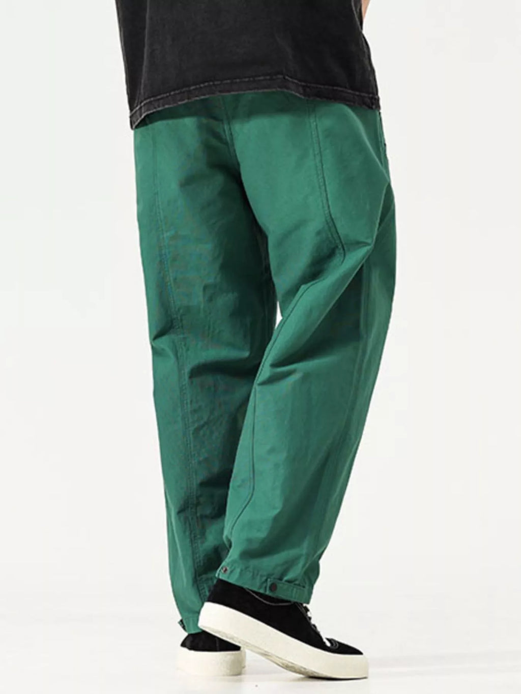 Men's emerald green cargo pants close-up, roomy legs with seam lines and cuff