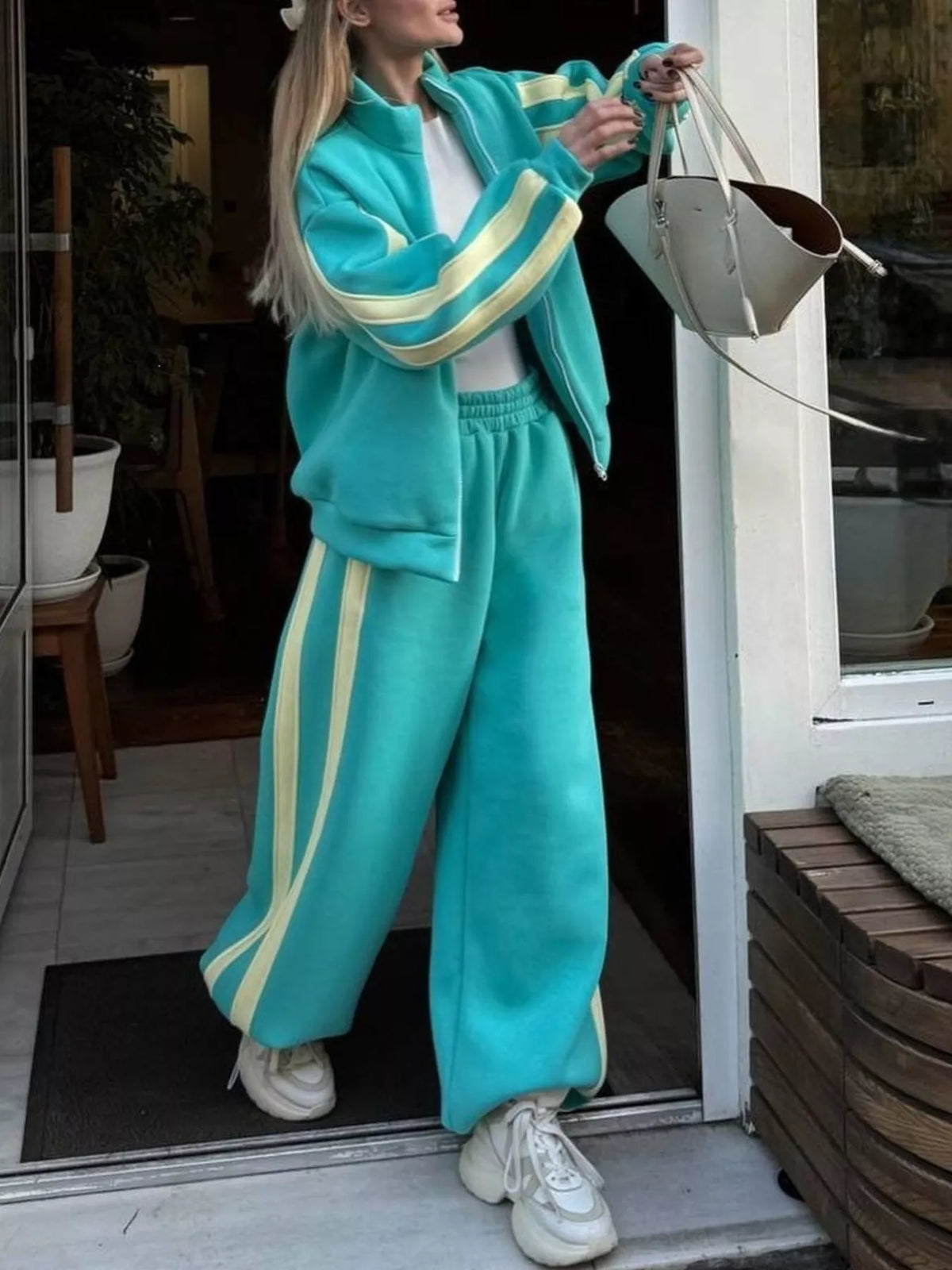 Teal zip-up top and wide-leg pants set with contrast stripes along sleeves and sides.