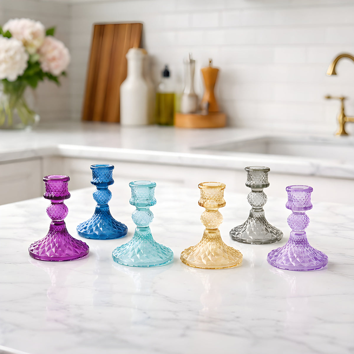 Glass taper holder set with purple, blue, gold, and smoke-gray holders on marble