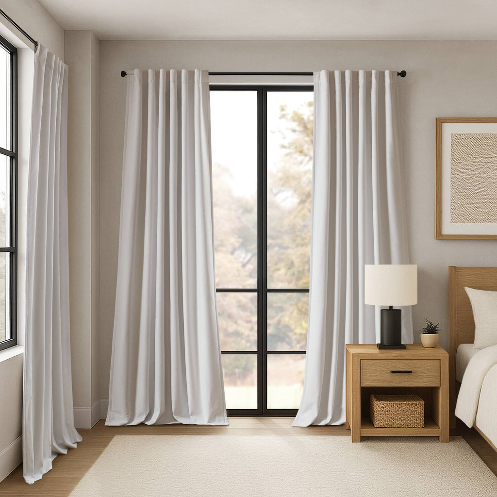 White blackout curtains on a rod with evenly spaced vertical folds
