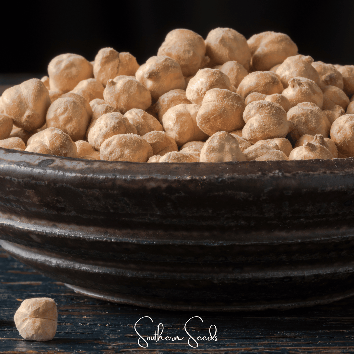 Dry chickpea seeds piled in a dark metal bowl