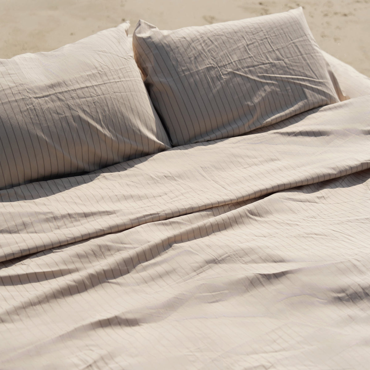 Light gray striped sateen sheet set with folded flat sheet and pillowcases