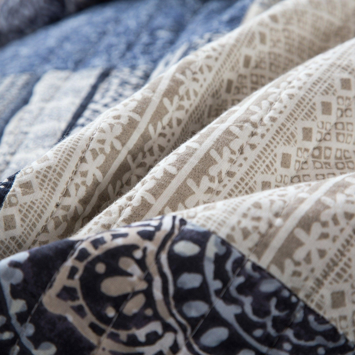 Close-up of white and denim blue patchwork quilt fabric with decorative band detail