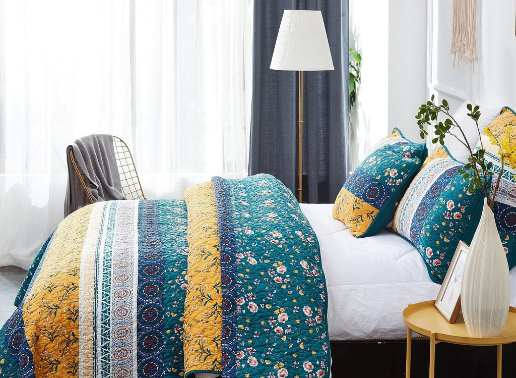 Patchwork quilt set with teal floral quilt and yellow accent pillows on white bed