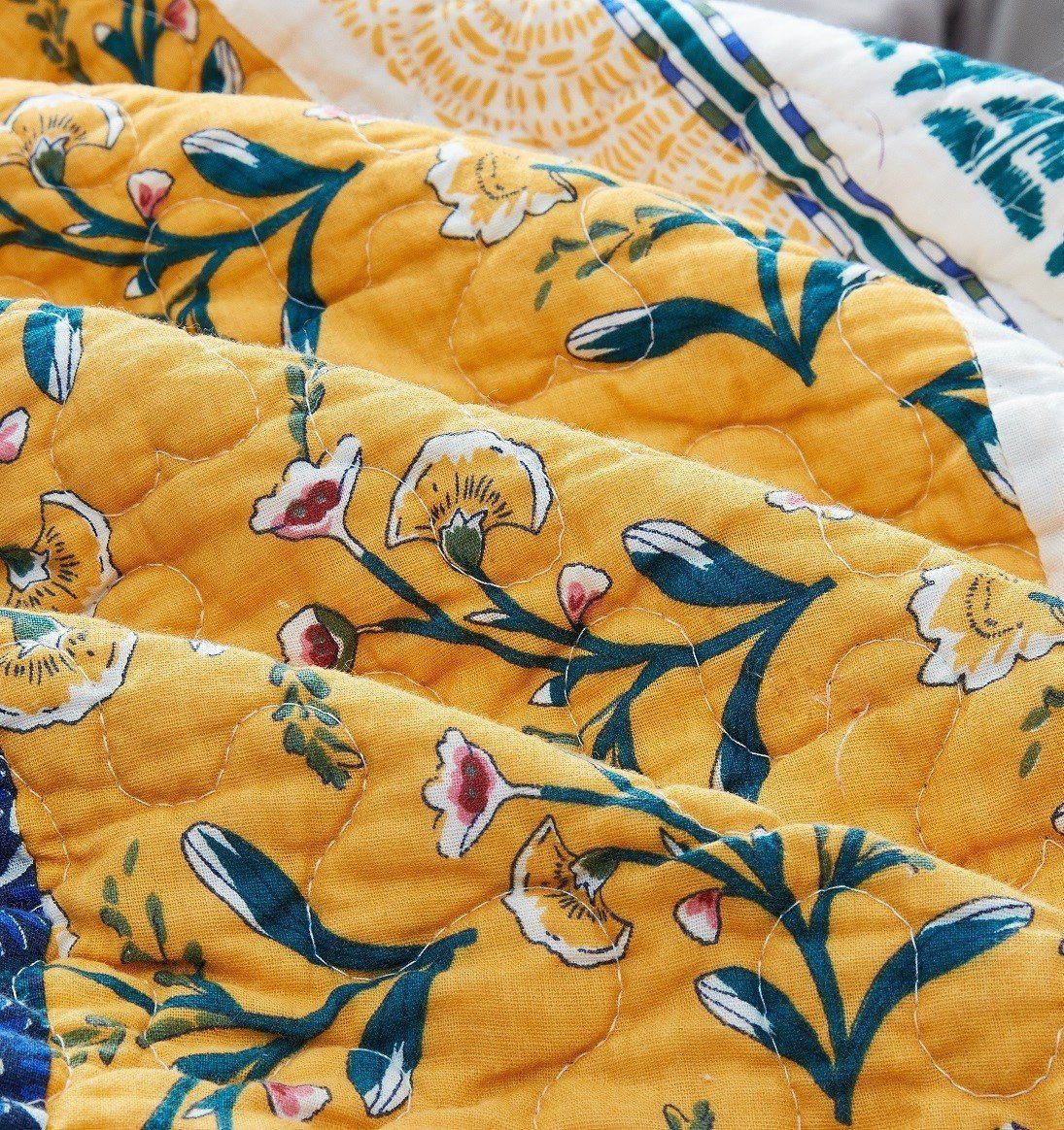 Quilt fabric detail: golden yellow floral print with stitched quilting texture