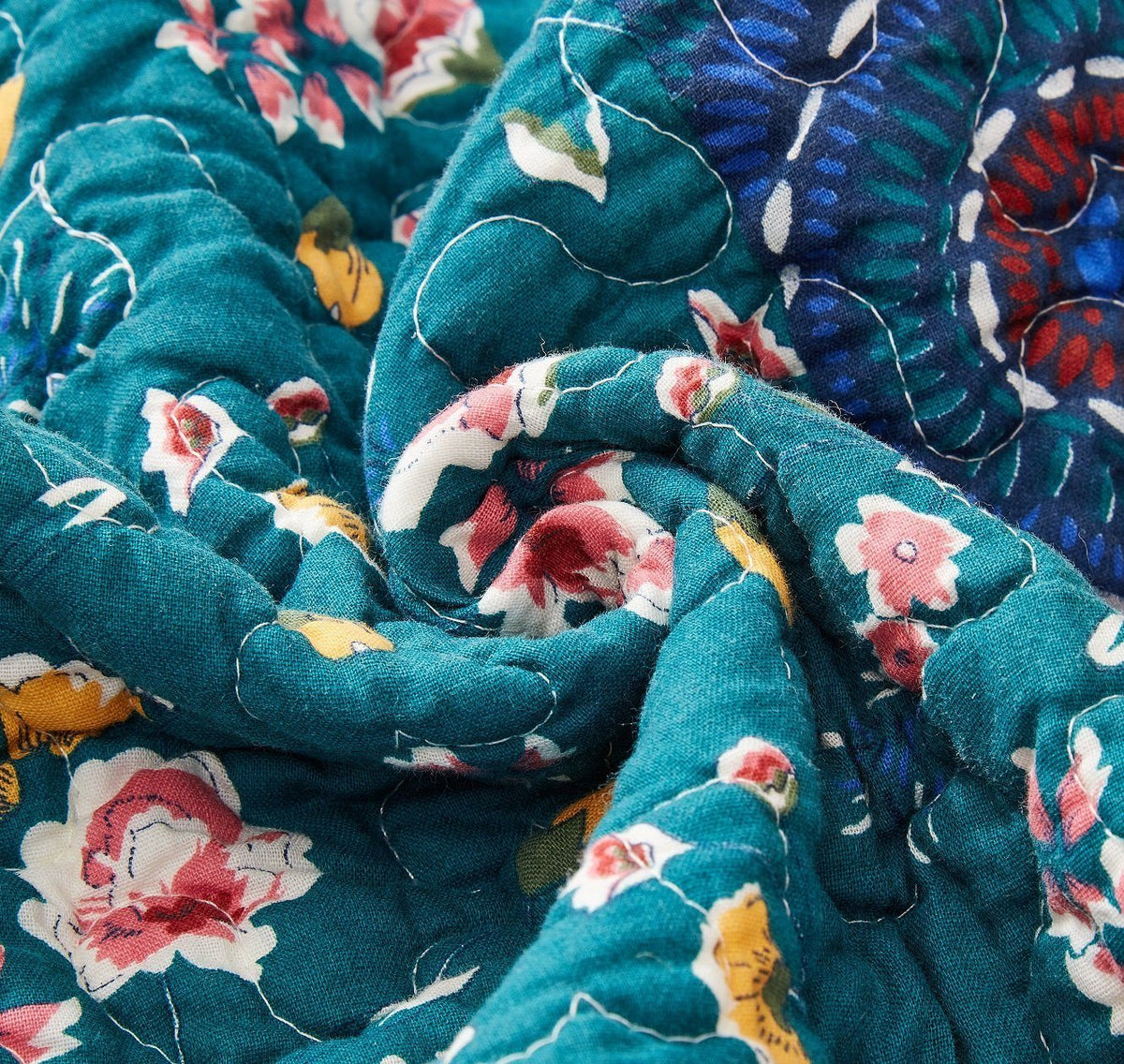Quilt fabric detail: teal background with multicolor floral pattern and soft folds