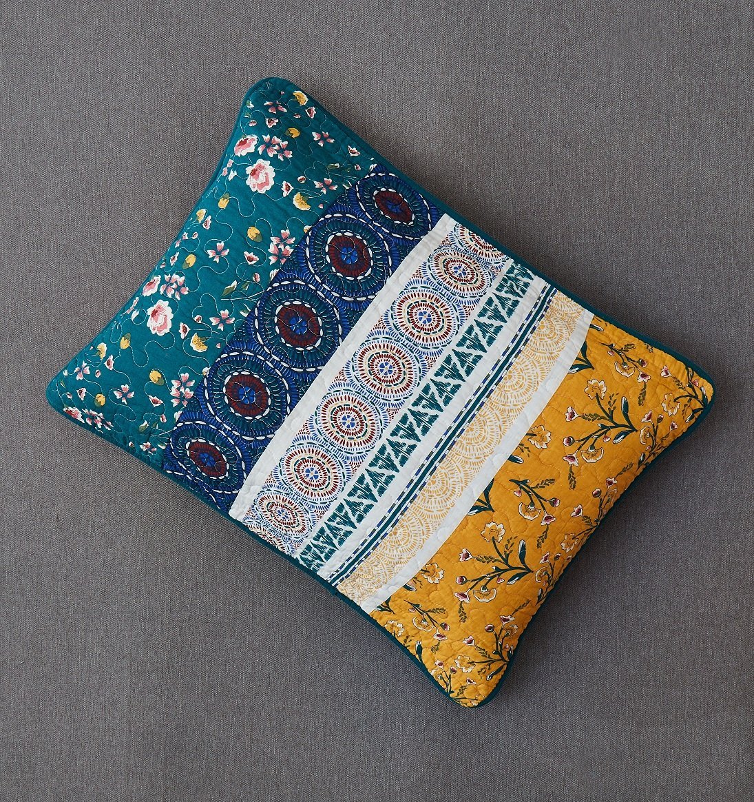 Decorative patchwork pillow in teal floral with yellow panel and blue circular motifs