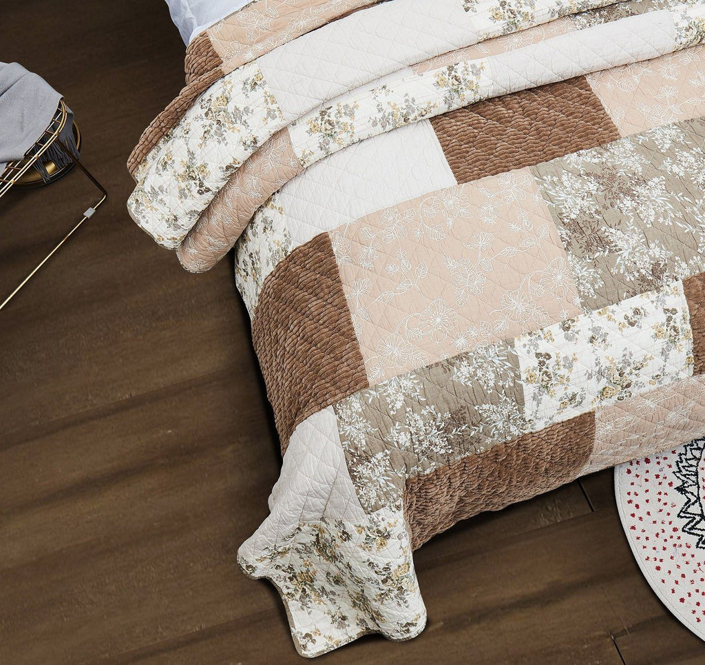 Quilted bedspread corner with floral trim and brown-beige patchwork squares