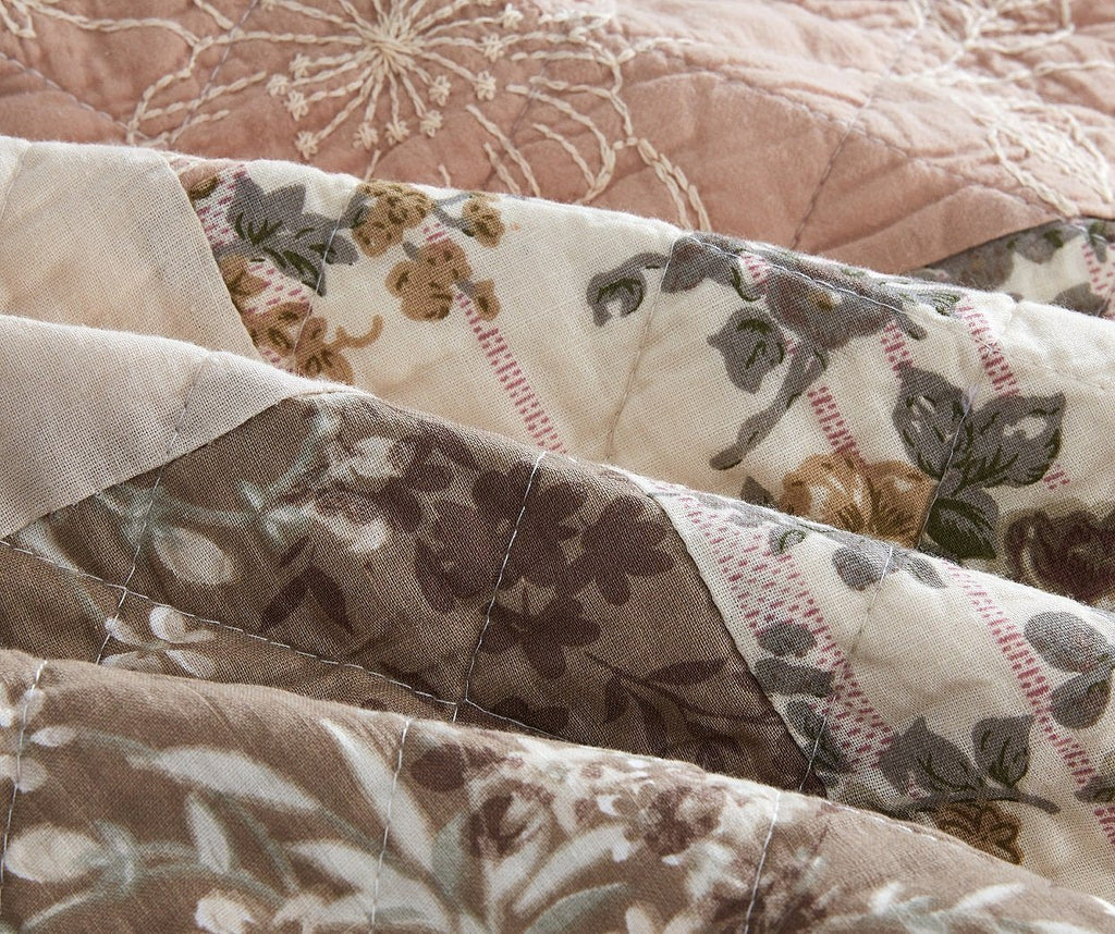 Quilted bedspread close-up with floral sprig print and dusty rose backing