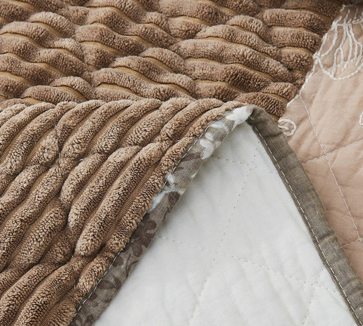 Quilted bedspread close-up with ruched textured brown fabric and stitched edge