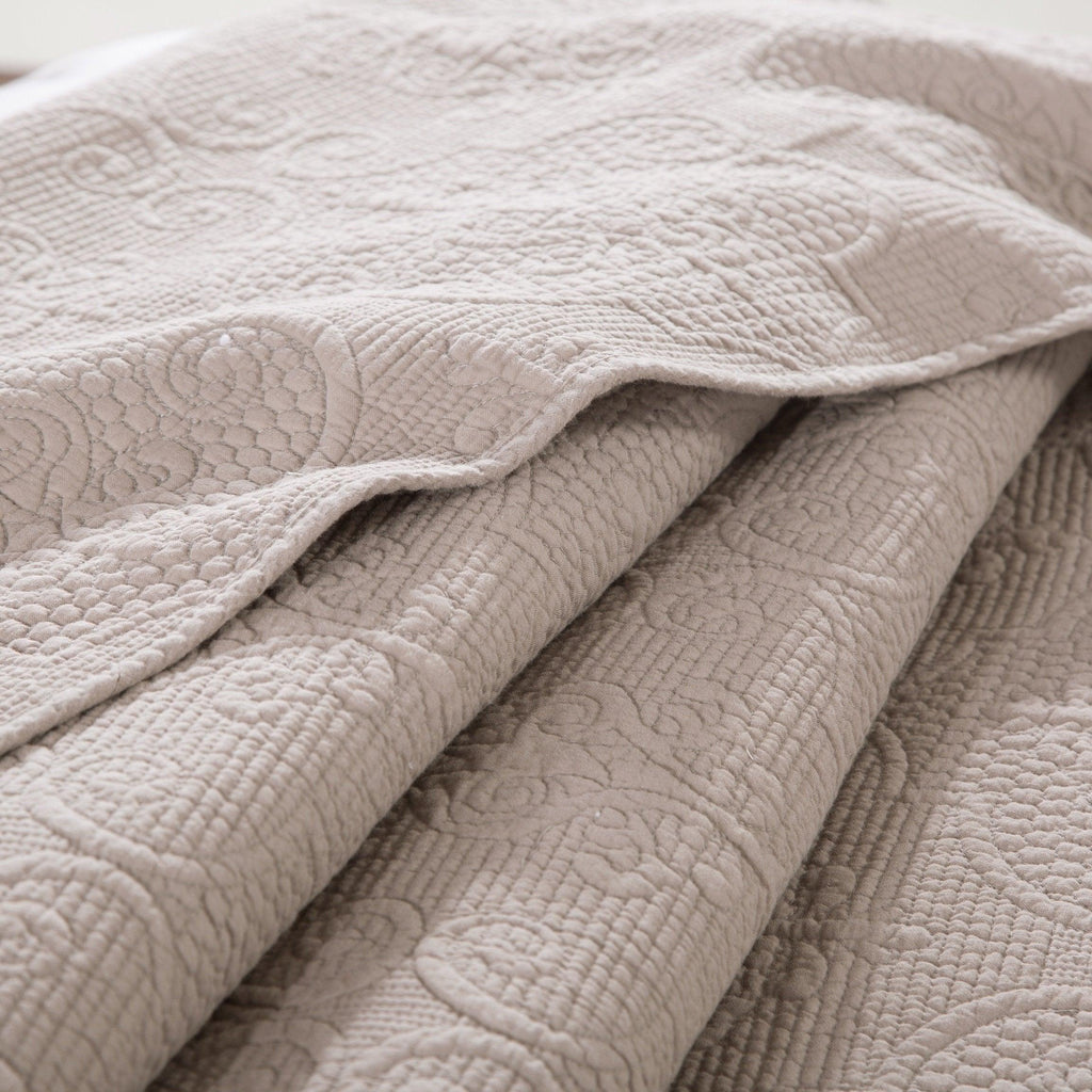 Folded quilted bedspread showing raised swirl stitching and layered matelasse quilting