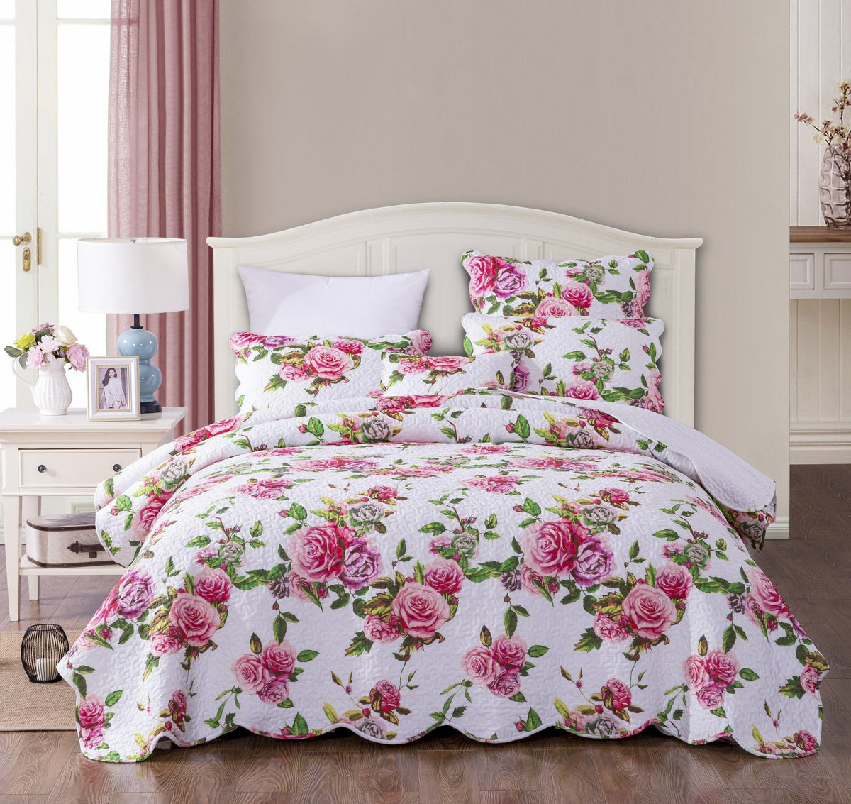 Pink rose floral quilt set on bed with matching shams, quilted white background