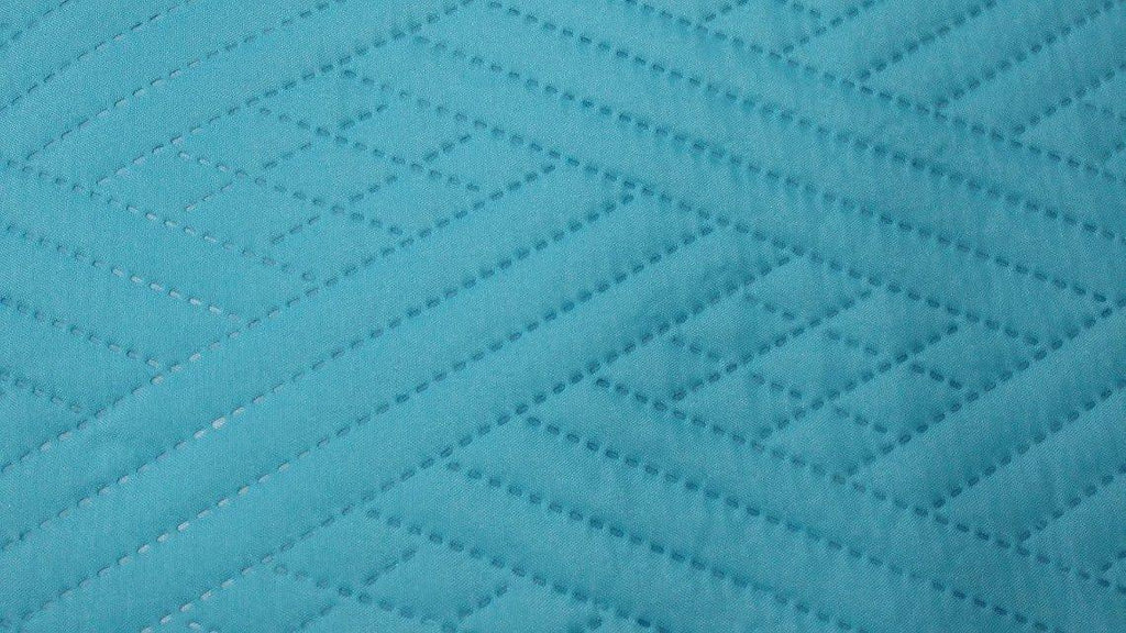 Close-up of turquoise teal quilted bedspread showing diamond wave stitching