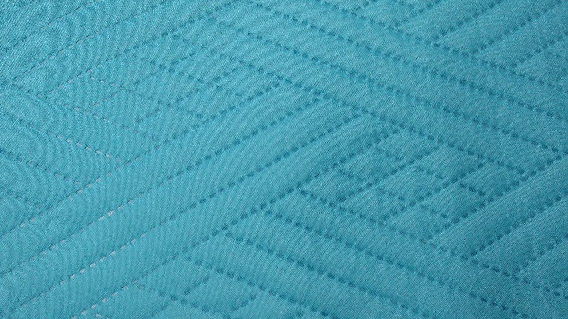 Close-up of turquoise teal quilted bedspread showing diamond wave stitching