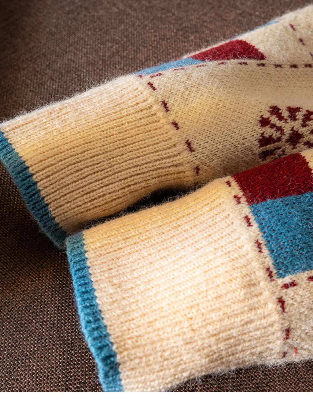 Men's sweater sleeve cuff with beige knit and teal trim; red and blue patch details