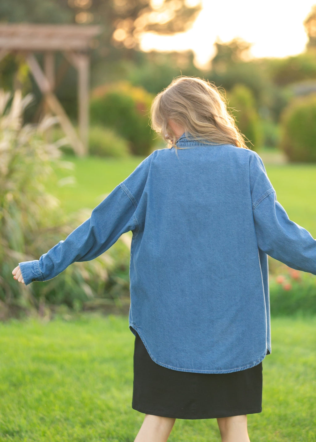 Denim button-up top in medium blue, back view with long sleeves and button placket.