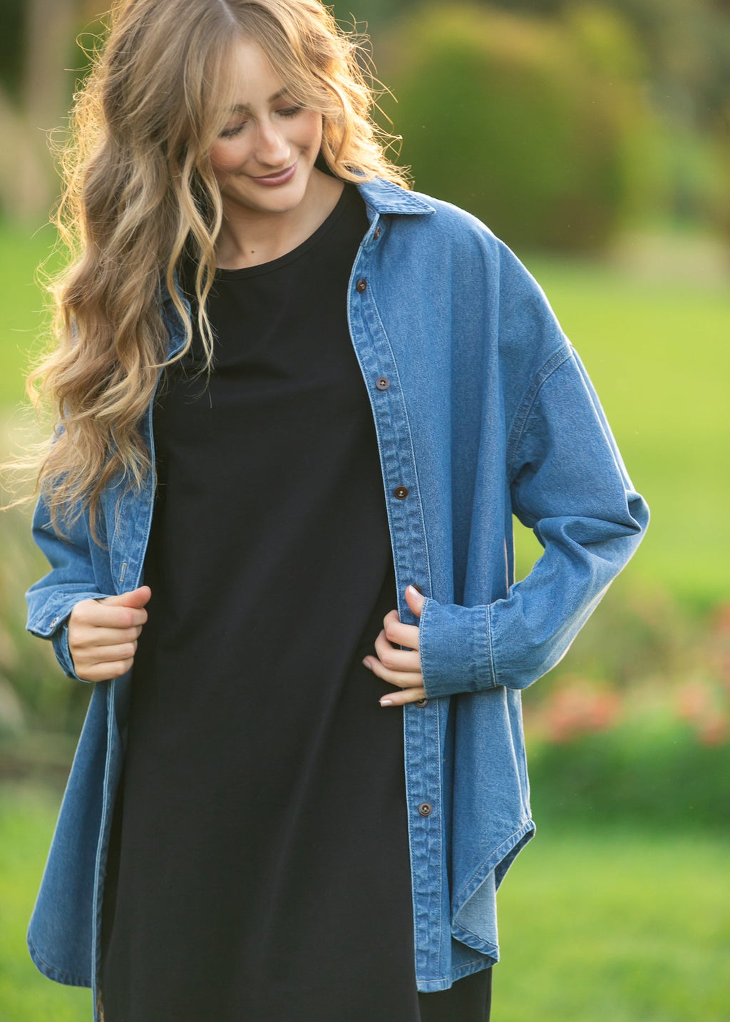 Blue denim button-up top close view with button front and long sleeves over black top