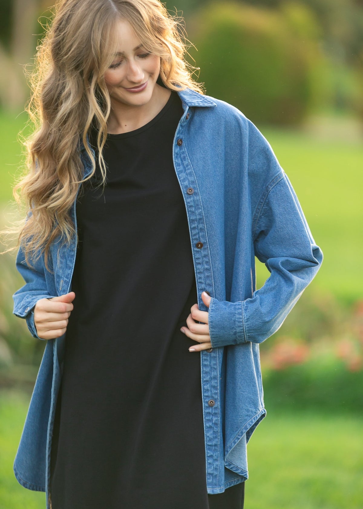 Blue denim button-up top close view with button front and long sleeves over black top