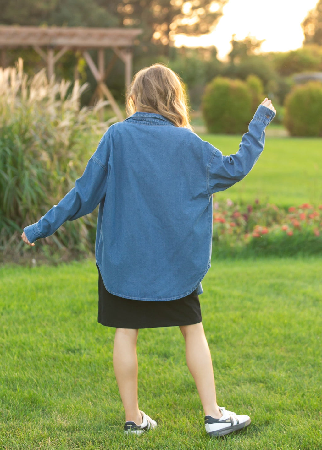 Blue denim button-up top from back, long sleeves and button closure, below-hip length