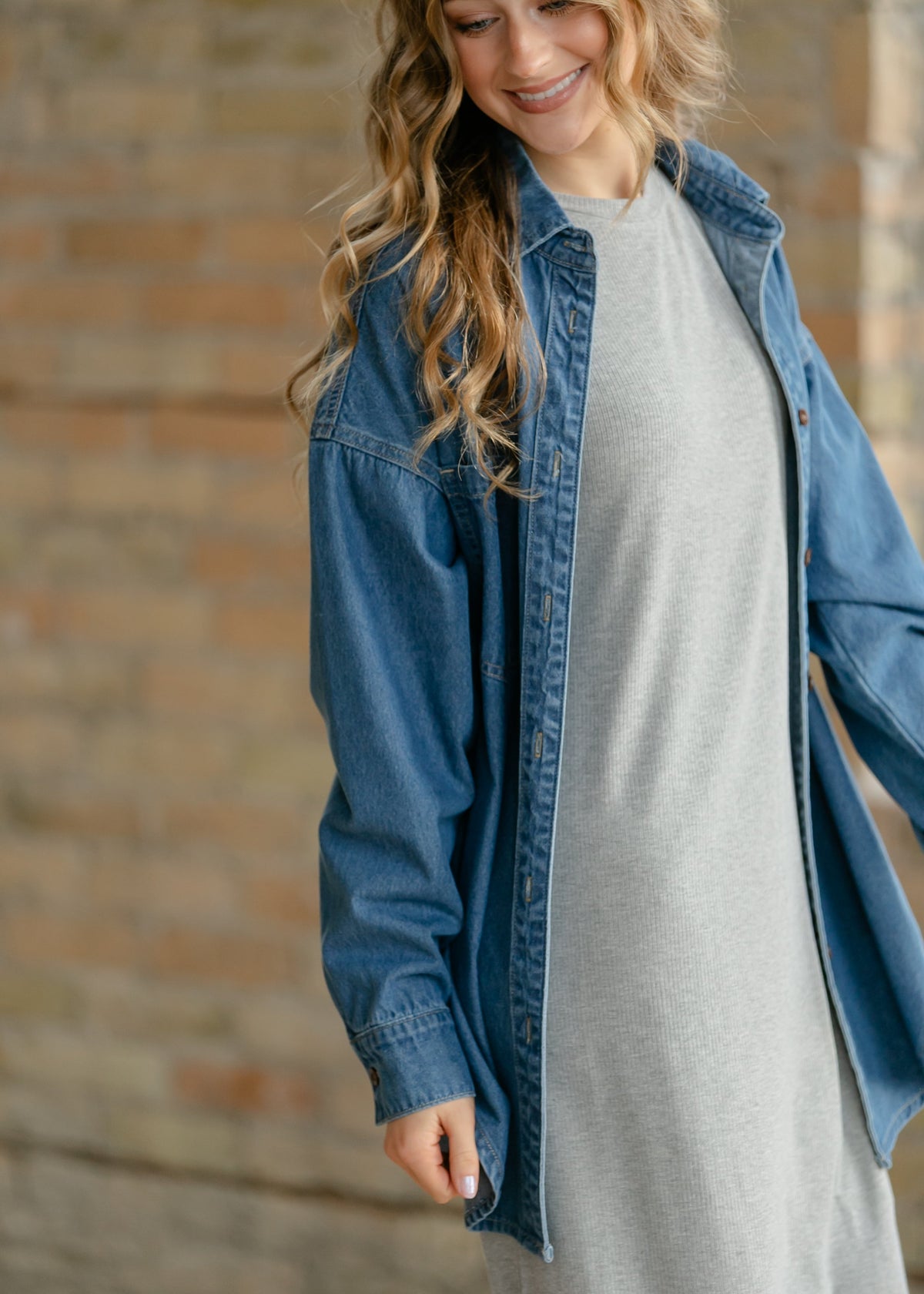 Blue denim button-up top detail: button placket and chest pocket on long sleeve