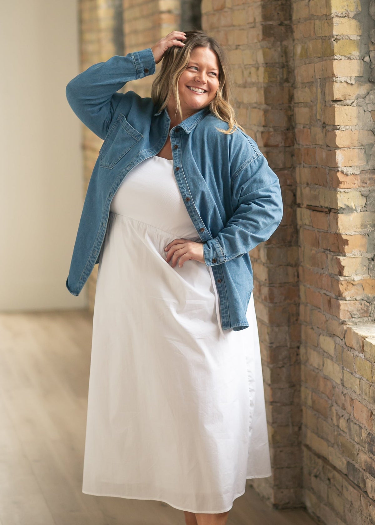Blue denim button-up top with stand collar and long sleeves, worn over a white skirt