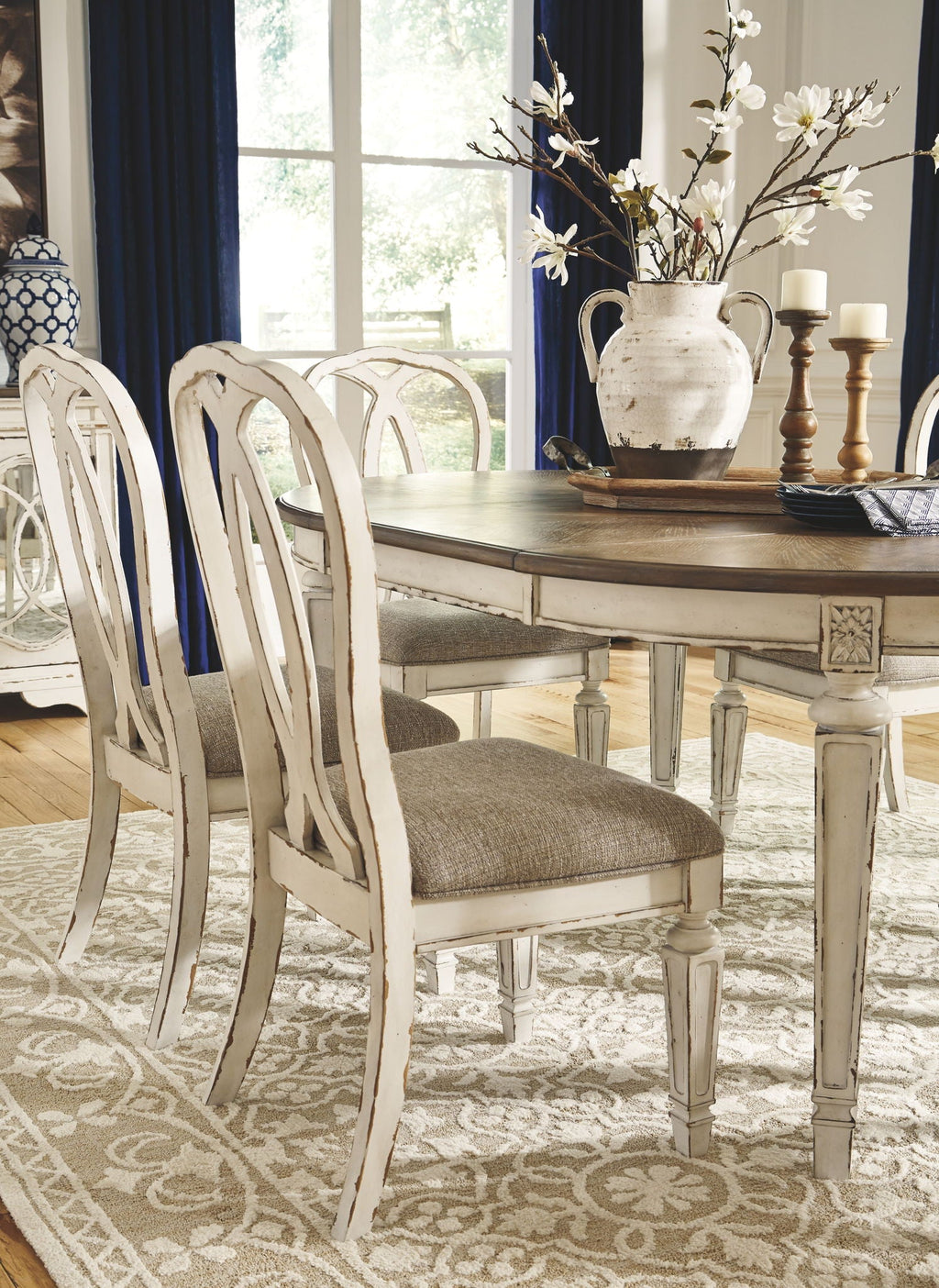 White oval dining table set with ladderback chairs and taupe seat cushions