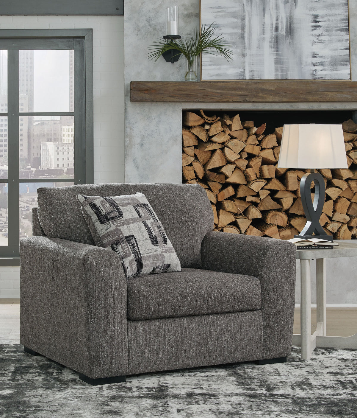 Pewter upholstered chair and a half with sloped seat and patterned accent pillow