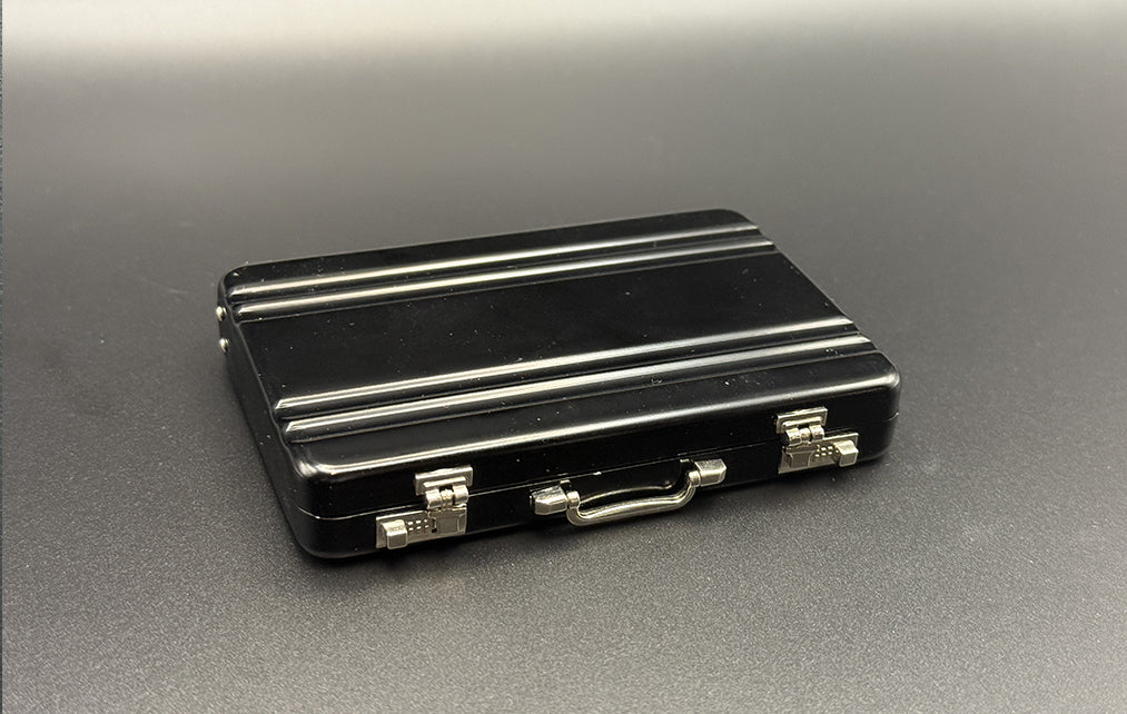 Black mini briefcase with chrome latches and handle, top view.